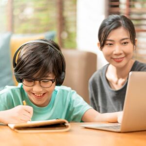 cheerful-asian-child-boy-online-lesson-study-from-home-conceptasian-child-hand-up-answer-question-from-online-teacher-asian-boy-sit-with-mom-dad-learn-from-laptop-living